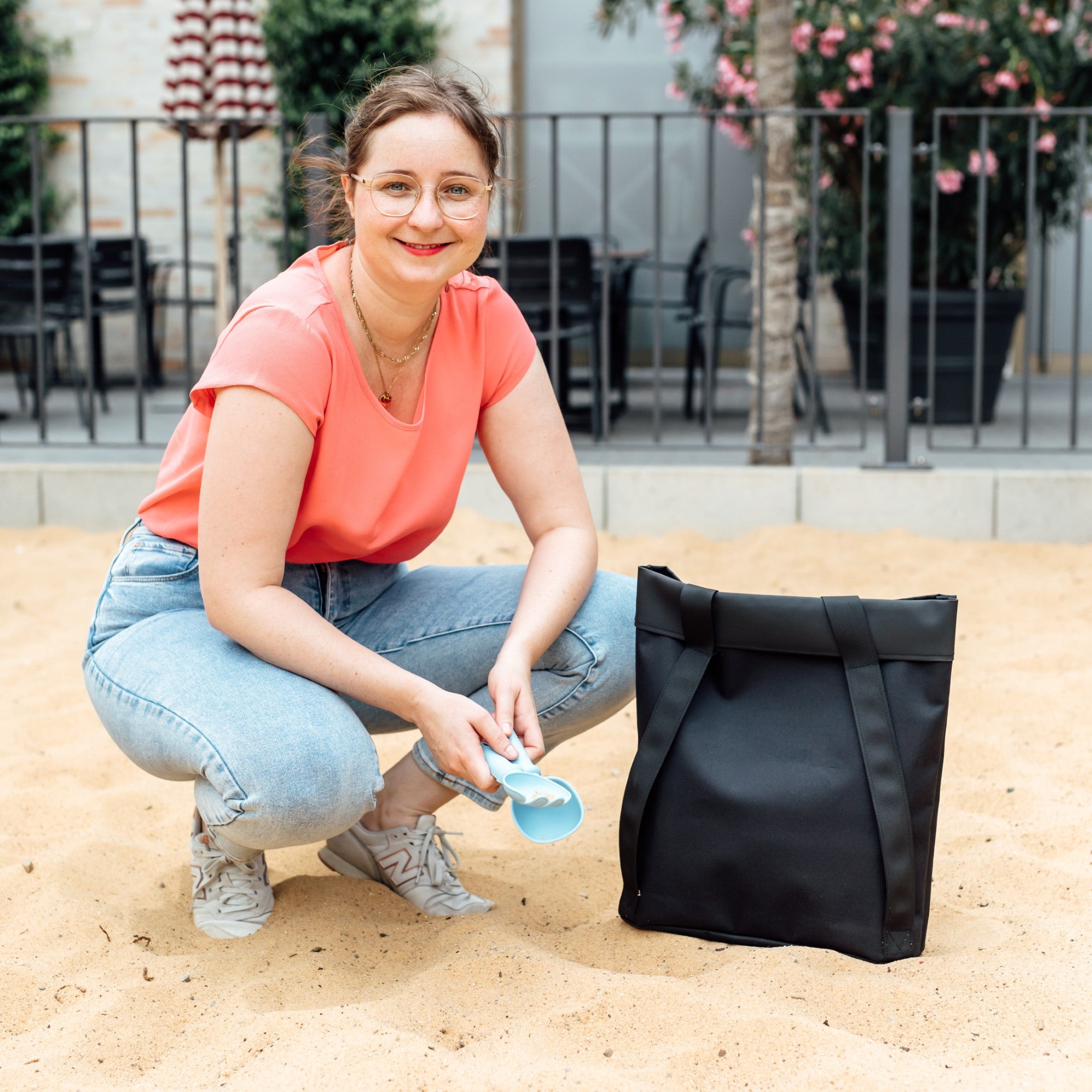 Frau mit minimalistischer Rucksack-Tasche ONE in Sandkasten auf Spielplatz